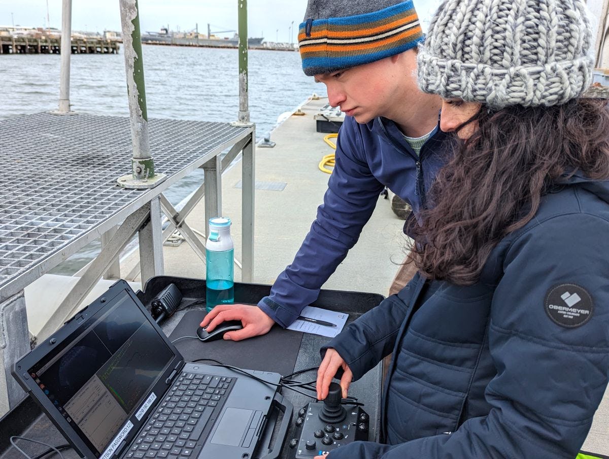 2 Stevens students checking data from underwater robot on a boat