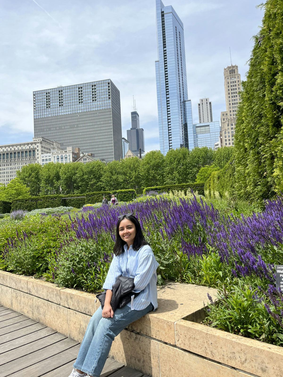 Rhythm Goyal sits in front of purple flowers with the Chicago skyline in the background.