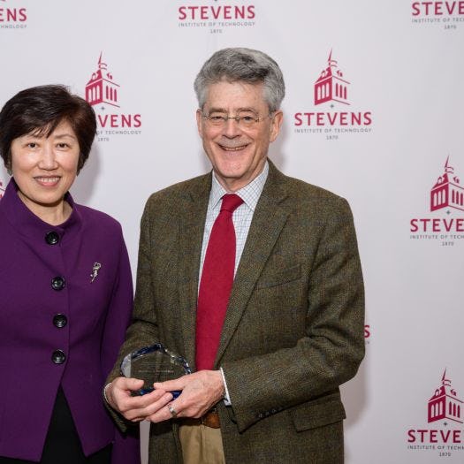 Jean Zu and Bob Gilman standing in front of a Stevens-branded backdrop