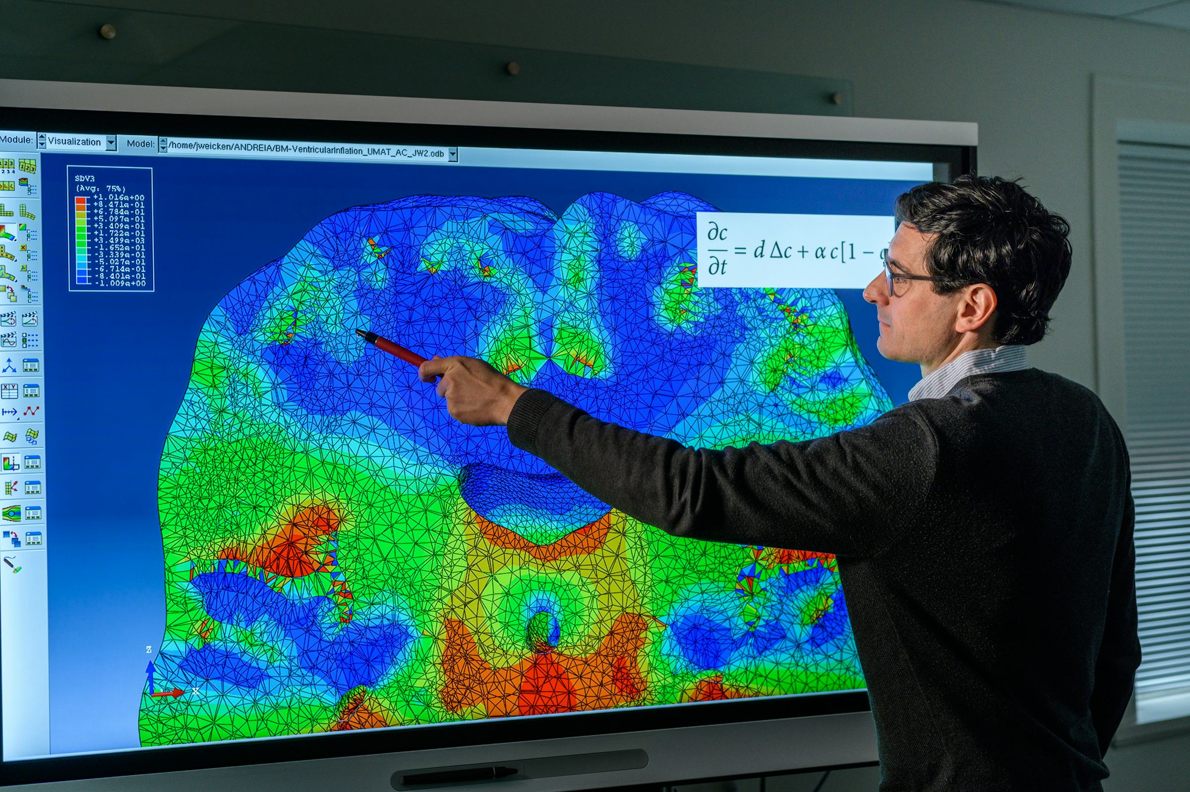 Stevens professor pointing to color image of a brain scan on large screen