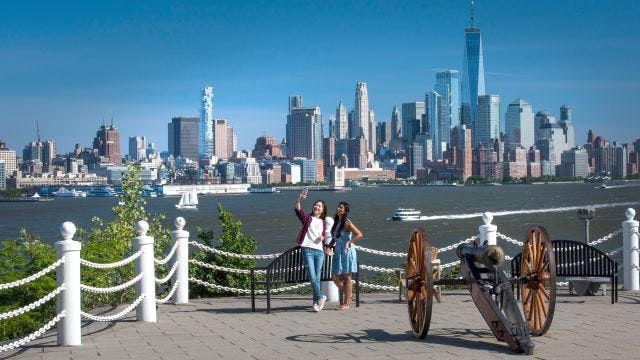 Two students pose for a selfie at Castle Point with a view of the New York Skyline.