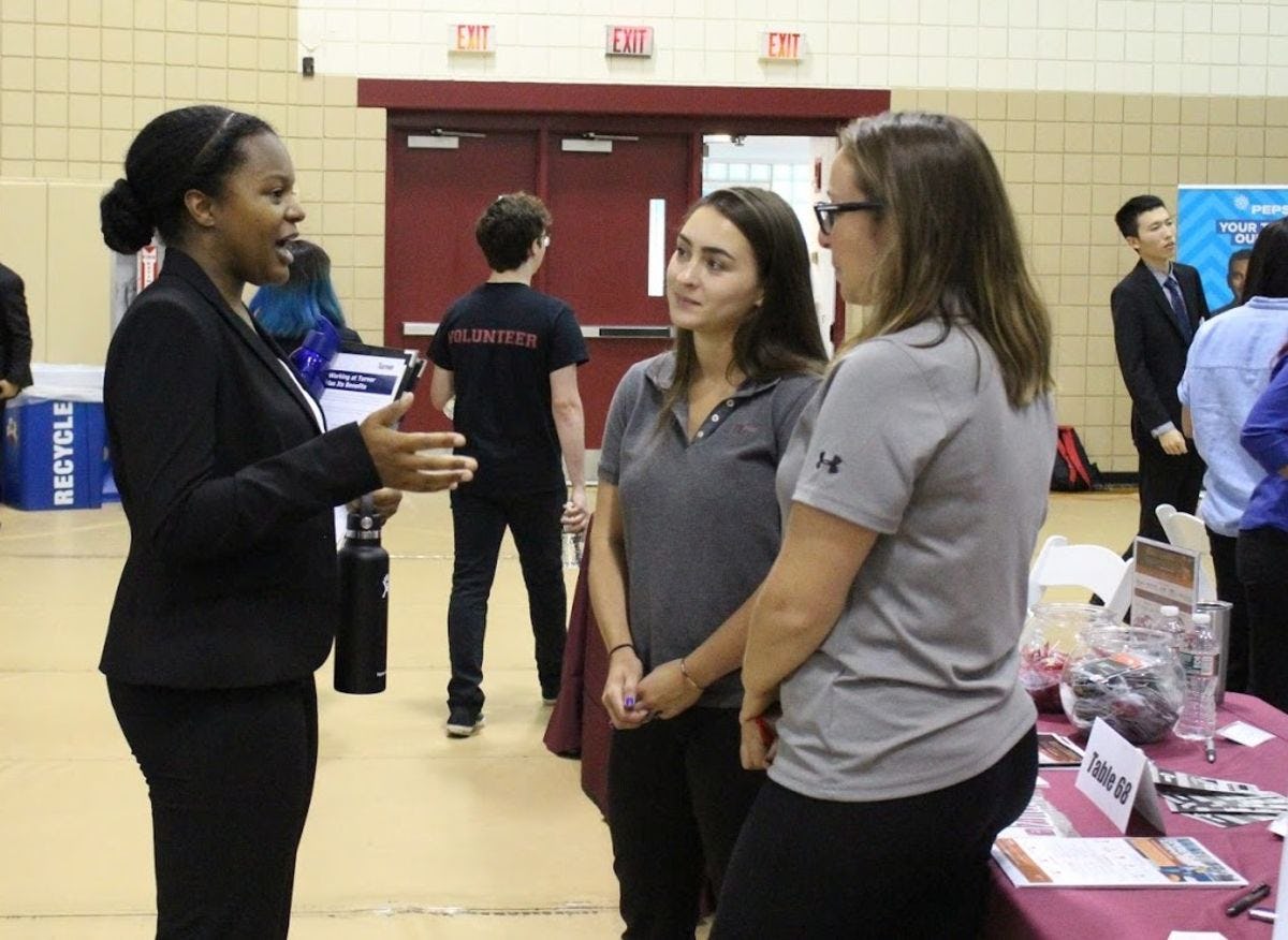 Stevens female student chats with two recruiters at their table