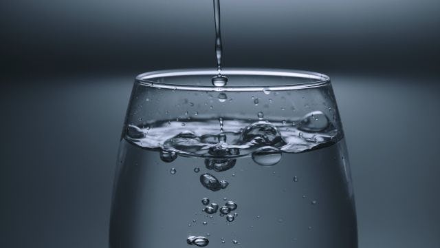 Glass of water with drops going in