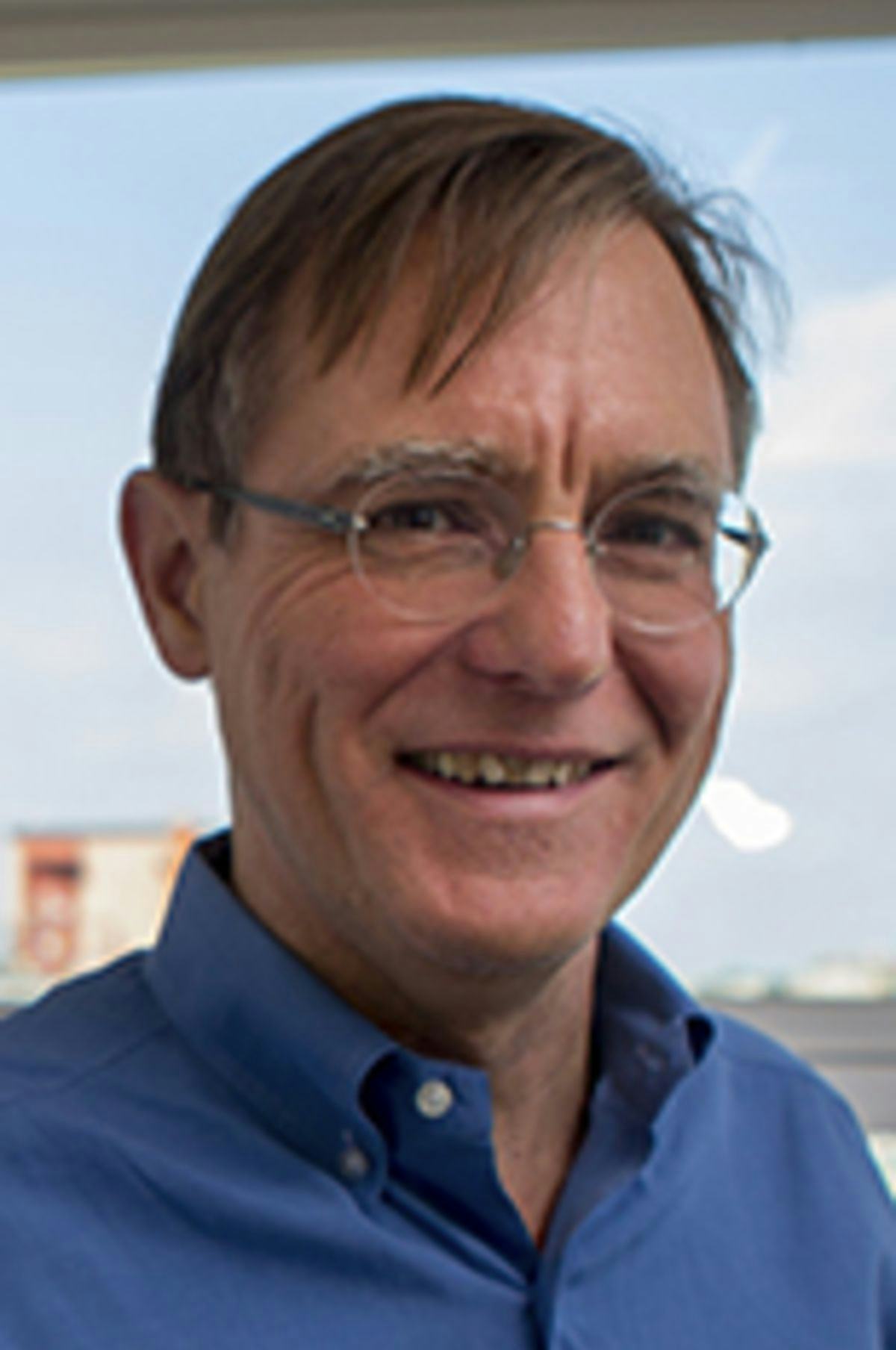 Headshot of Dr. Nickerson in a blue shirt with the Hoboken skyline in the background.