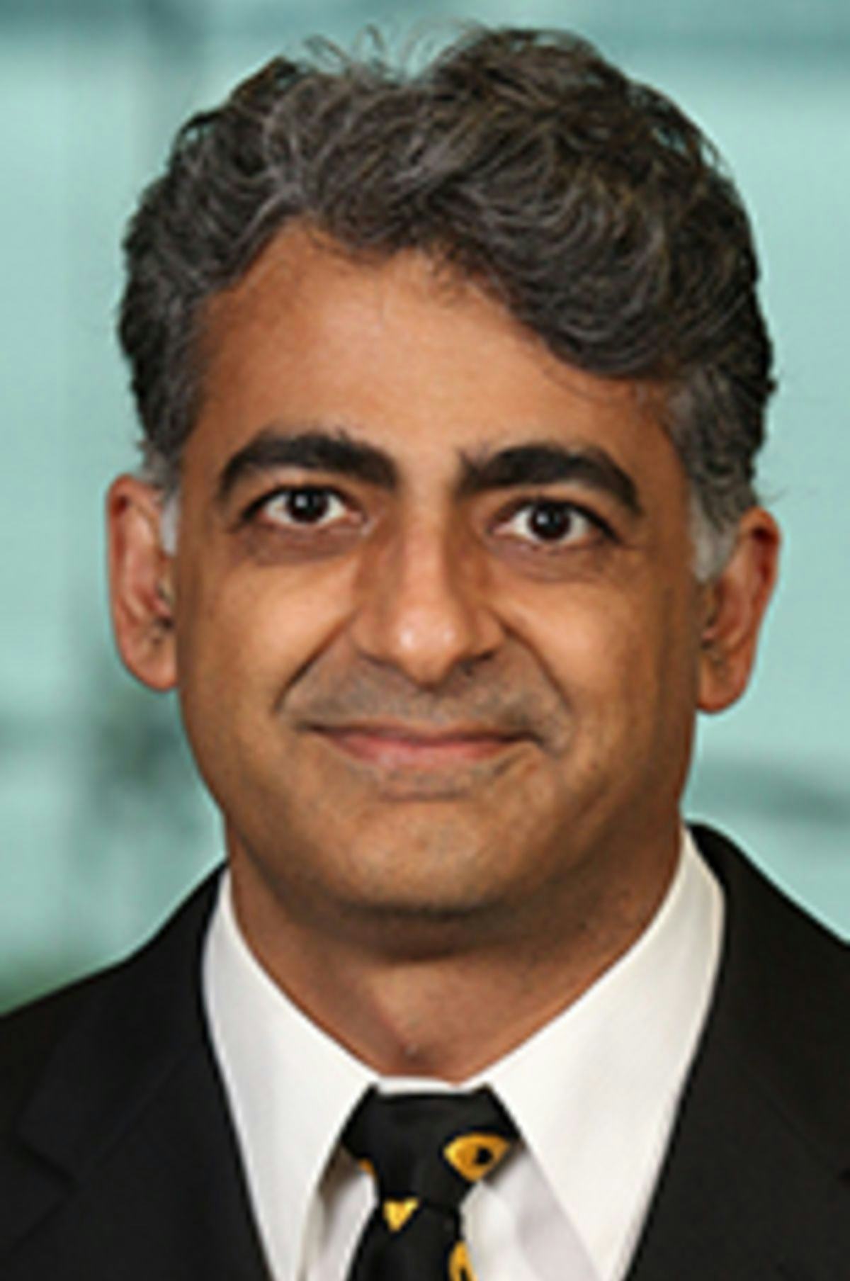 Headshot of Dr. Murad Mithani in a black jacket and dark tie with the New York City skyline in the background.