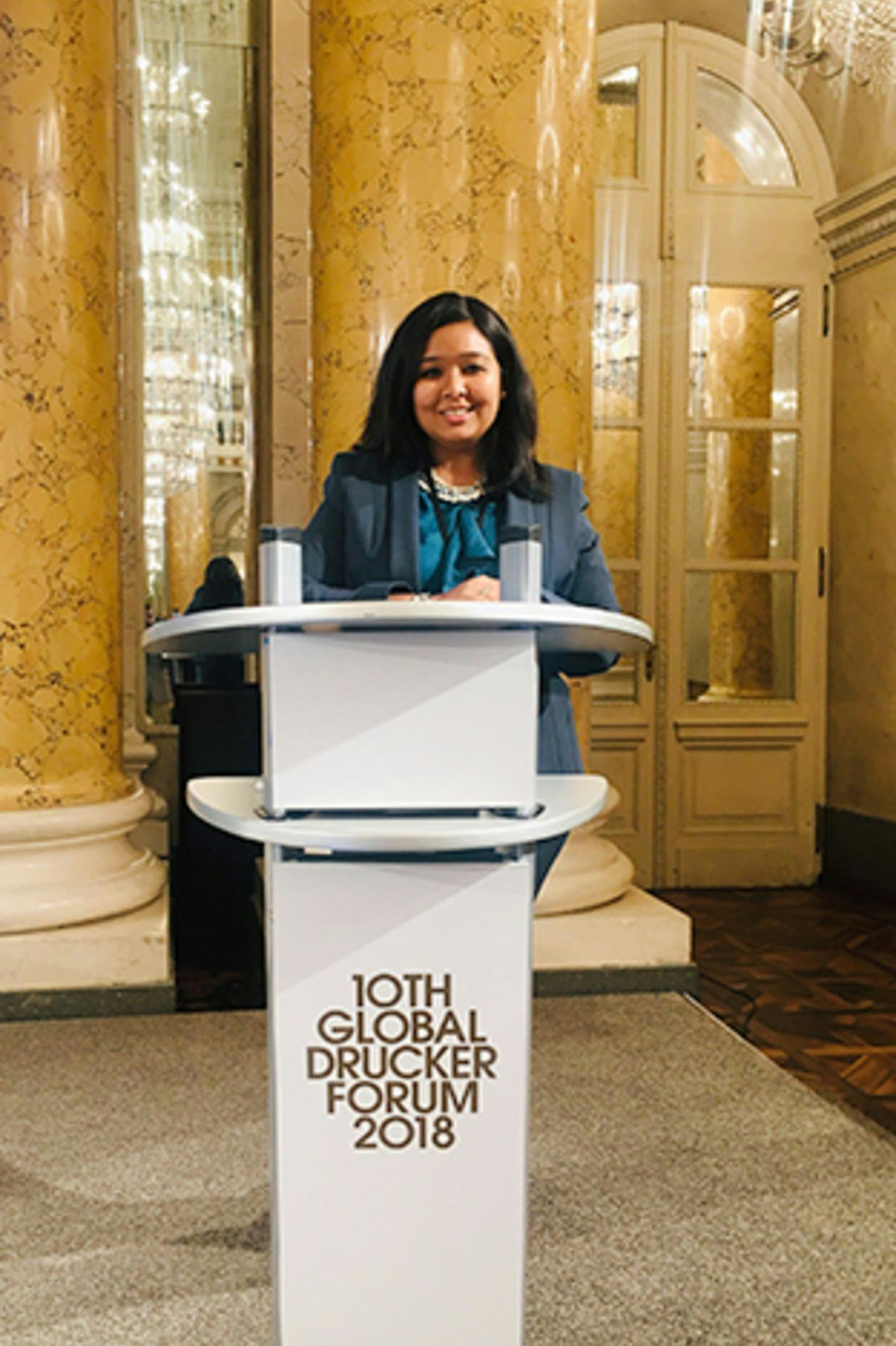 Kanika Ghocha in front of the podium at the Drucker Forum in Vienna.