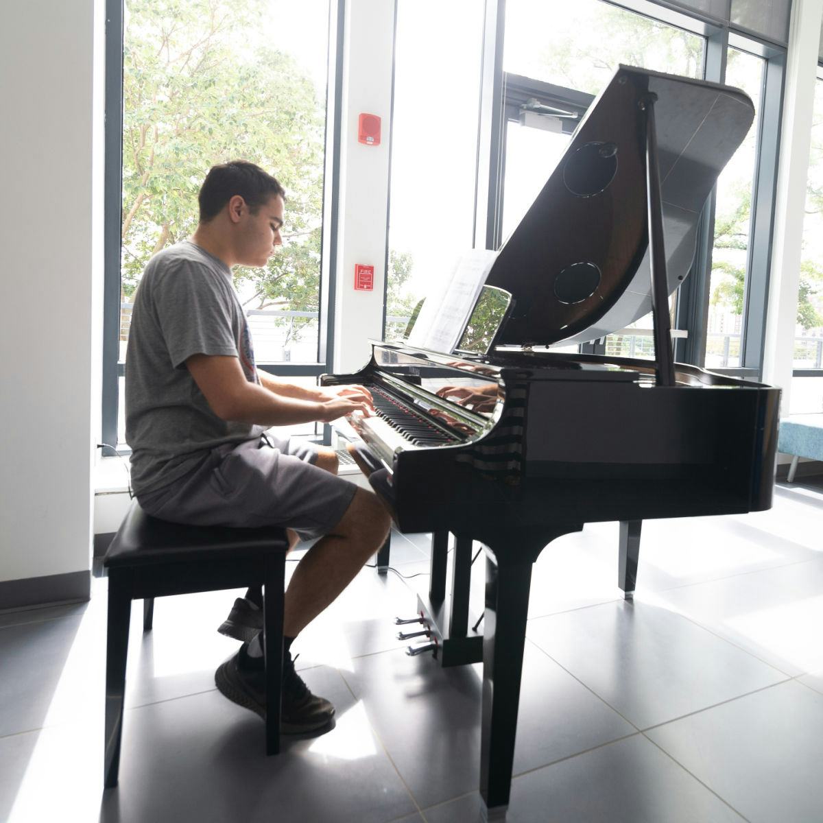Pianist in t-shirt plays baby grand piano in UCC.