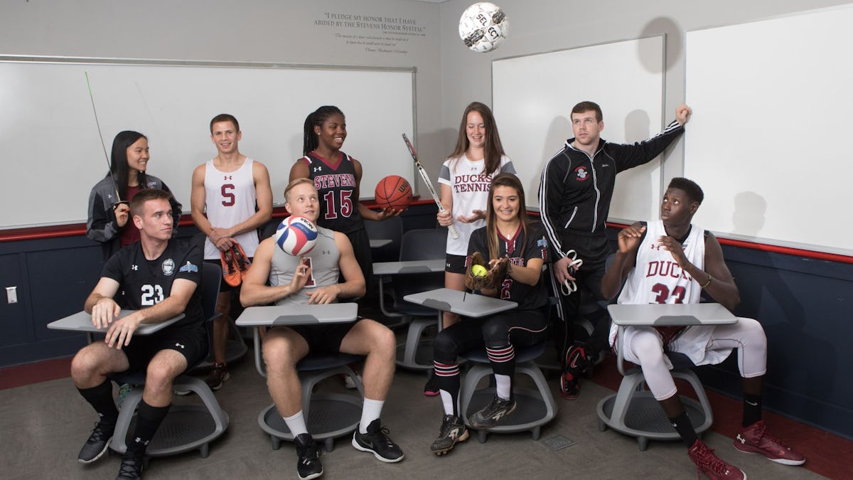 Eight student athletes sitting in class with sports props.