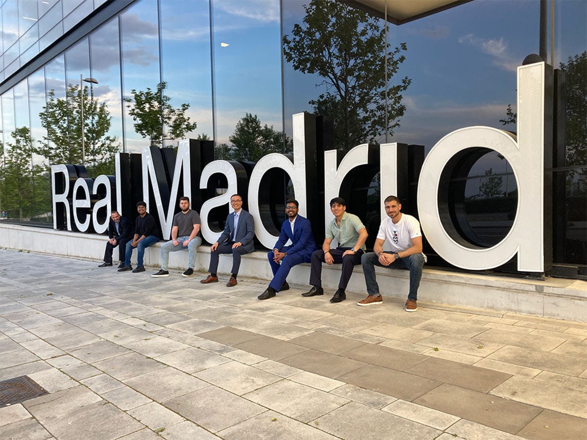 Stevens students and deans sitting in front of Real Madrid sign