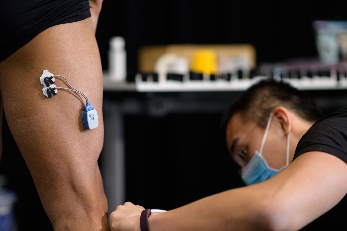 A rehabilitation measurement device is affixed to an athlete's upper thigh.