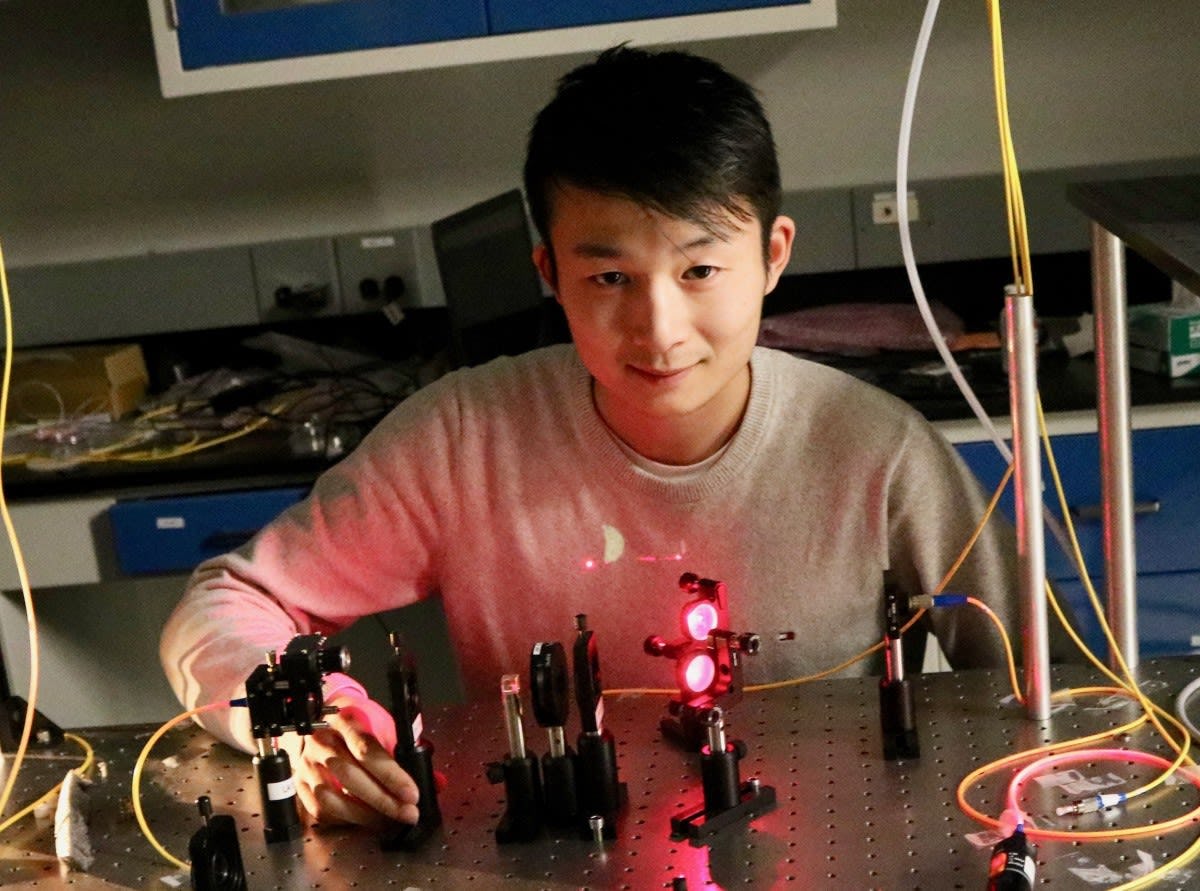 A student in the CQSE laboratory sitting in front of a laser