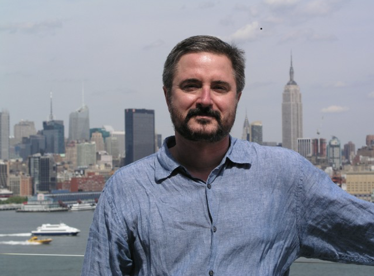 a photo of John Dzielski standing outside with the NYC skyline in the background