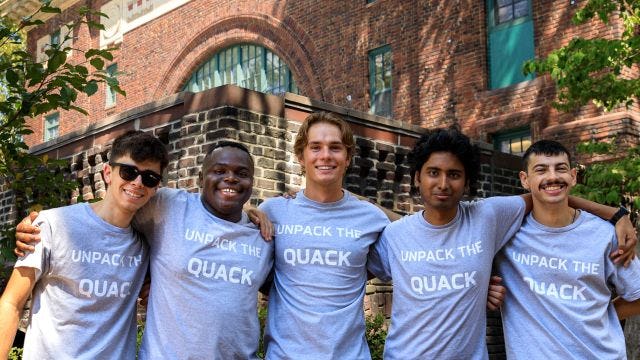 Five students stand with arms around each other wearing Unpack the Quack shirts