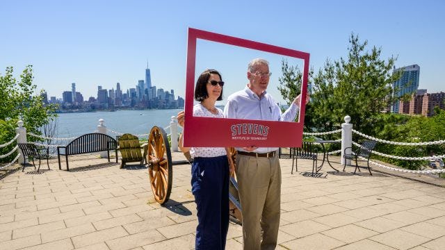 Alumni pose for a picture holding a frame at Castle Point