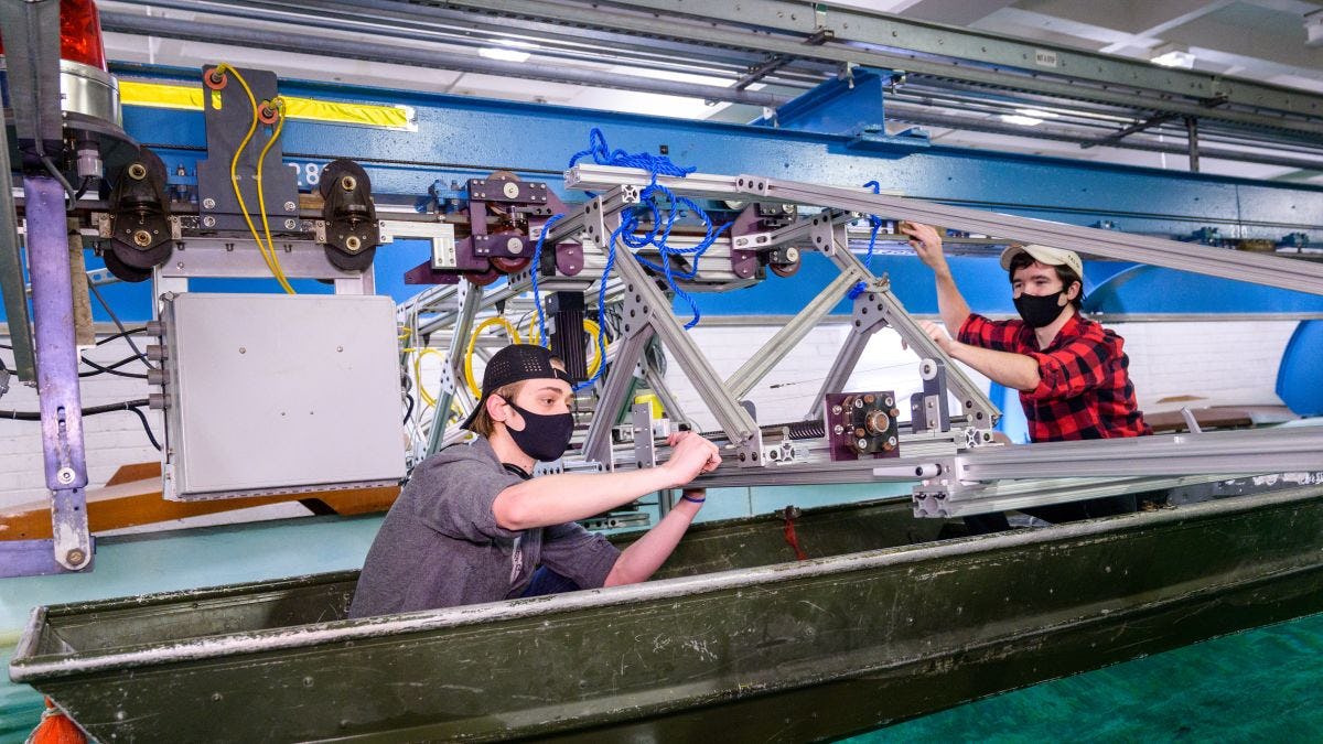 Students in boat in testing facility make adjustments