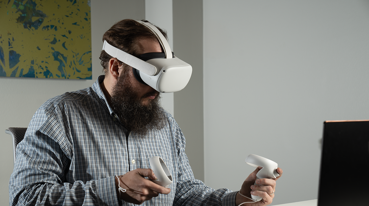 Professor Thomas Lonon wearing a VR headset and holding the hand controllers.