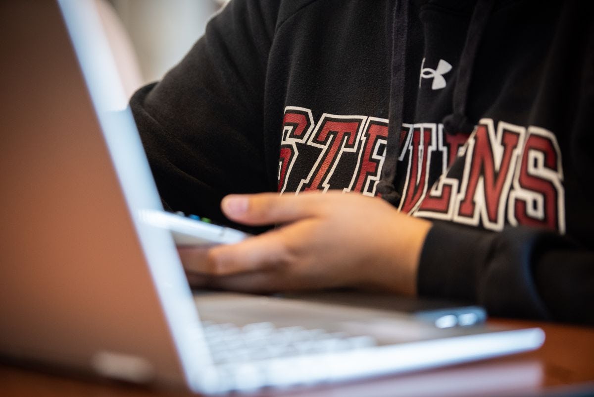 Student in black Stevens sweatshirt working on a laptop.