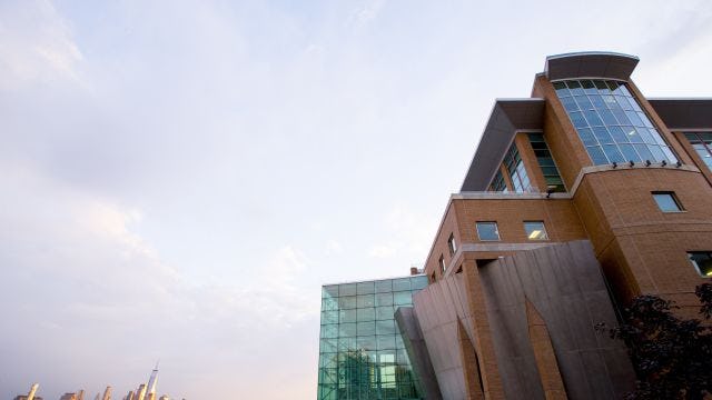 Exterior of the Babbio Center on the Stevens campus overlooking the New York City skyline in the background.