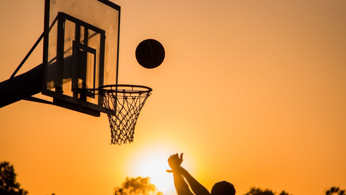 Man playing basketball in sunset