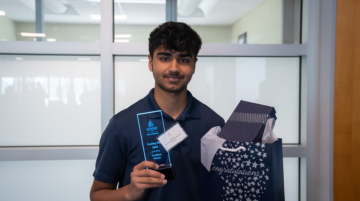 2024 Trading Day winner Arjun Arya holds his first-place trophy and gift bag.