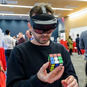 Attendee wearing VR goggles and holding Rubik's Cube at Stevens event