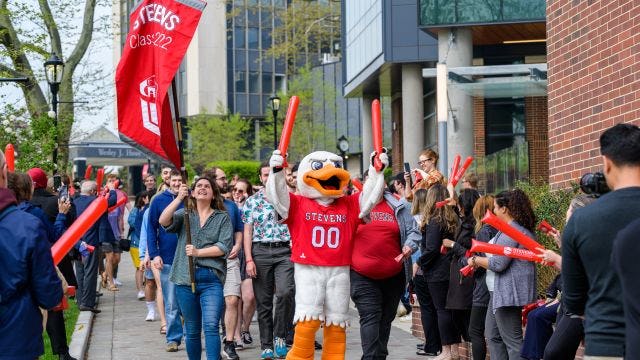 Graduating students walk on Wittpenn Walk with Attila and cheering crowds
