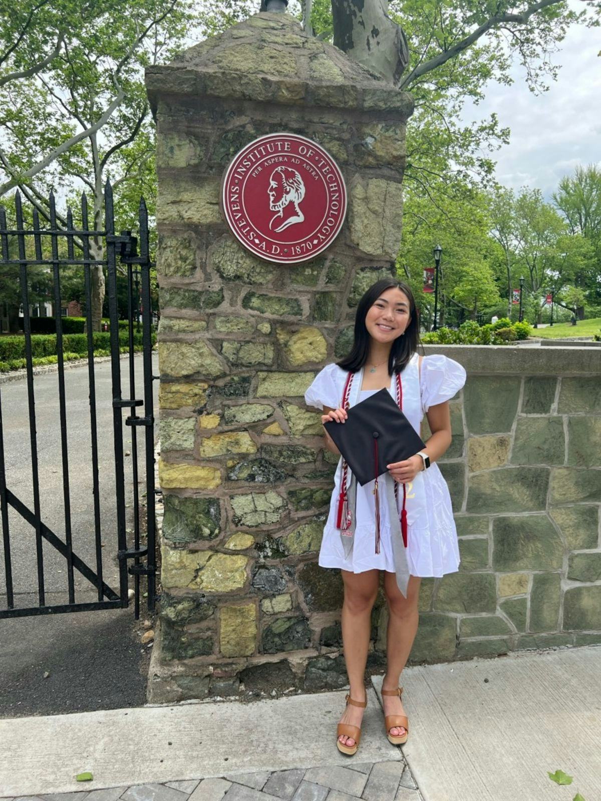 A photo of Lizzi Chu standing in front of the Stevens seal on campus