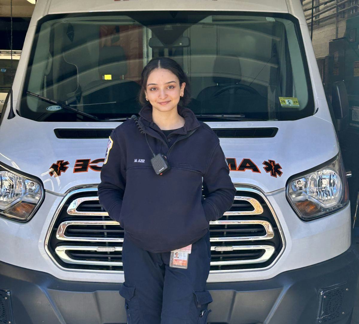 Malak Aziz ‘24 stands in front of an ambulance, dressed in her EMT uniform