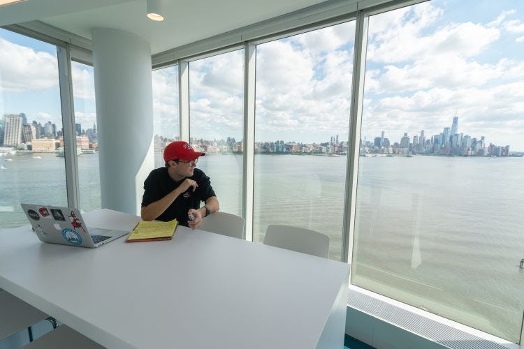 Student looking out window at New York skyline.