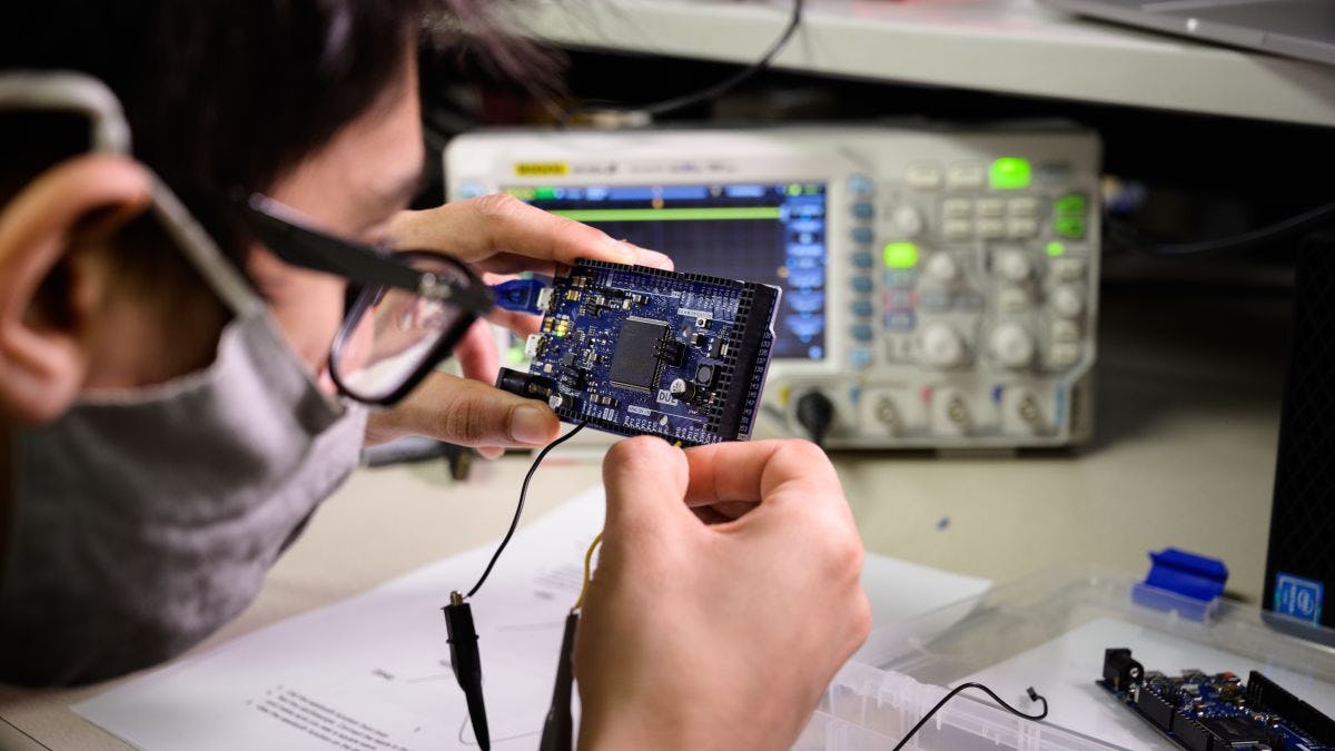 Student wearing glasses adjusts circuit board