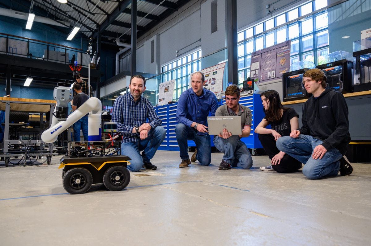 Associate Professor Brendan Englot and researchers observe and operate a mobile robot on wheels. 