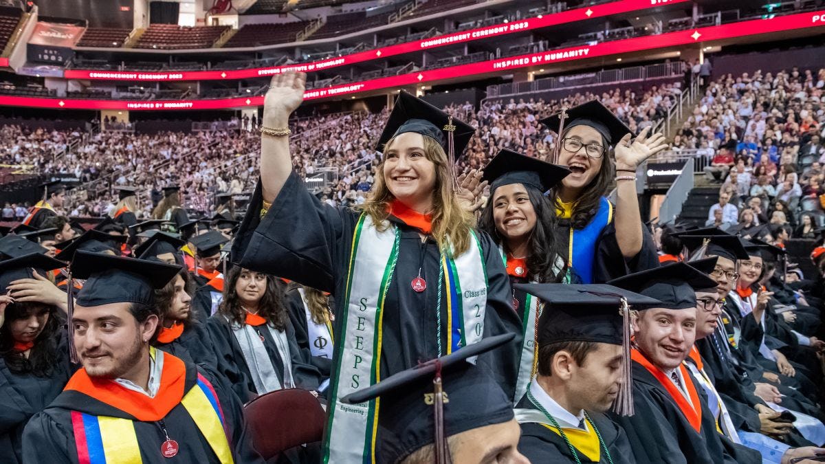 Graduates standing and waving to the crowd at the 2023 Commencement ceremony