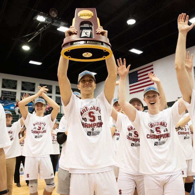 The Stevens men's volleyball team celebrates their championship win with the NCAA trophy.
