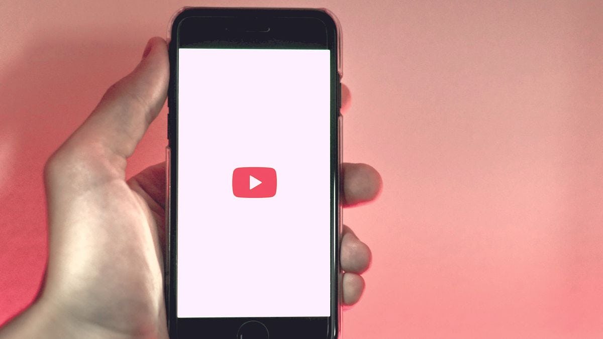 Hand holding phone with Youtube logo on screen