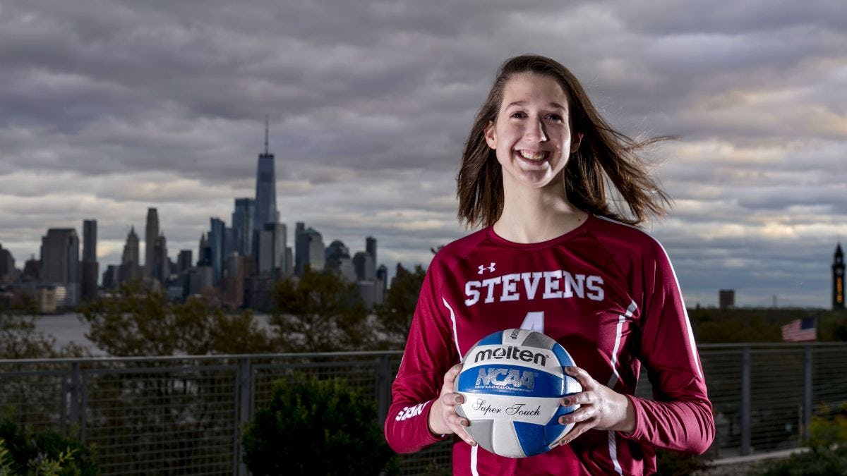Student Shelby Stewart posing with volleyball in front of New York City skyline