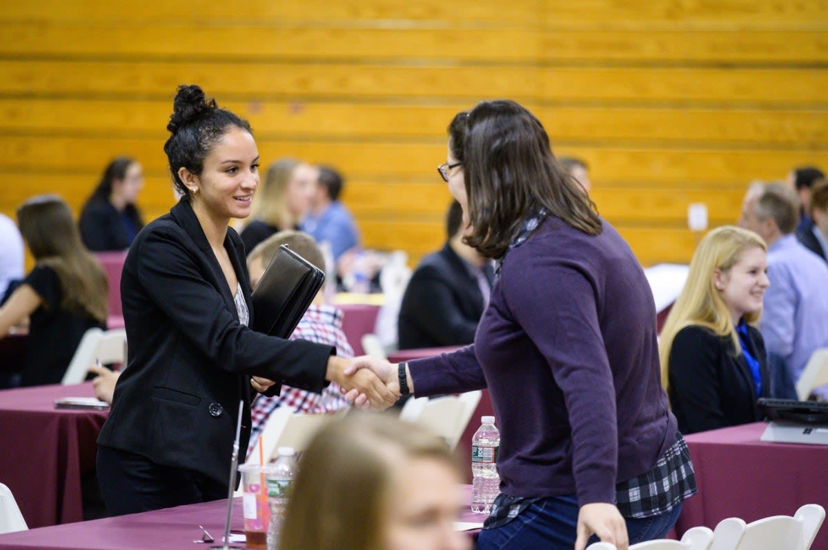 A female co-op student (left) shakes hands with a female recruiter (right)