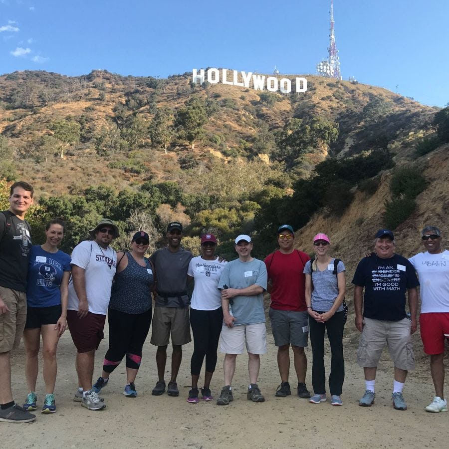 Southern California alumni pose on a hike in front of the Hollywood sign