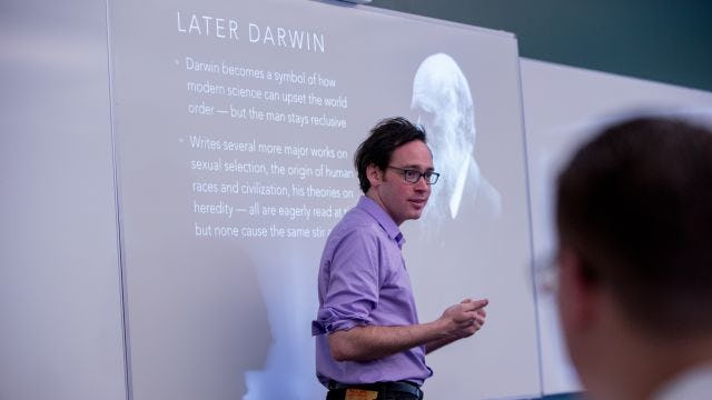Professor teaching with Later Darwin slide in background