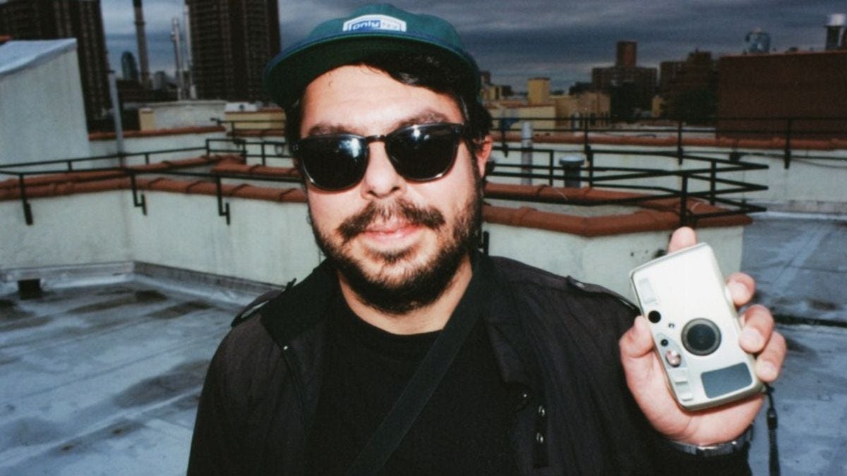 Photo of Kenneth Bachor, an alumni of the music and technology program at Stevens, on a roof, holding a digital camera.