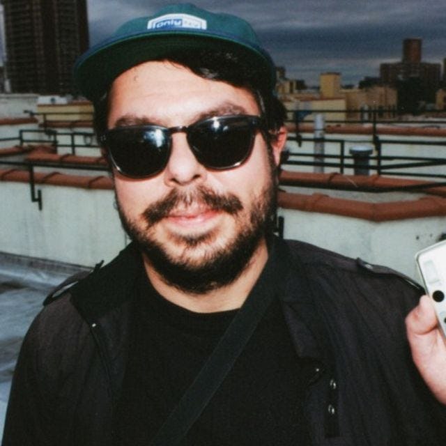 Photo of Kenneth Bachor, an alumni of the music and technology program at Stevens, on a roof, holding a digital camera.