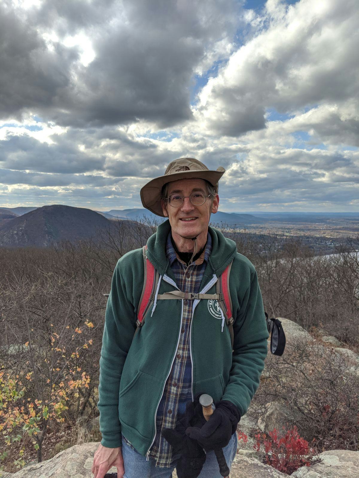 Computer Science Chair Dave Naumann smiles in front of a landscape while pausing on the Breakneck Ridge trail