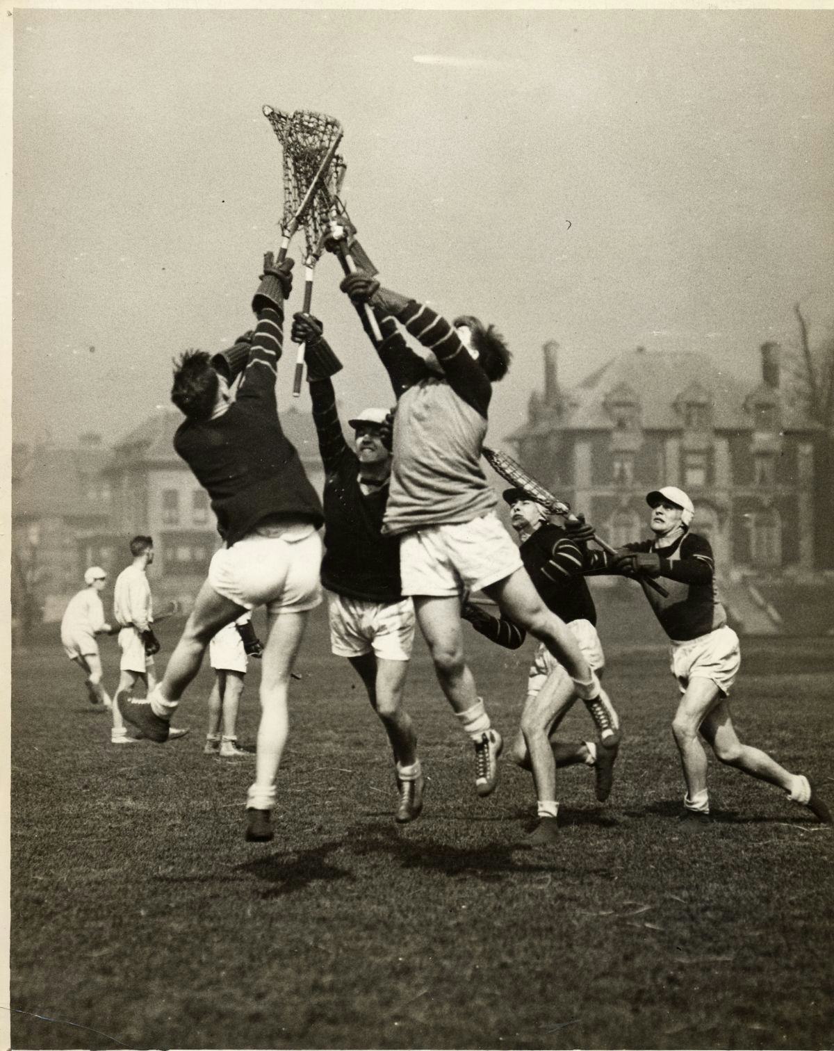 Black and white photo of Stevens Men's Lacrosse team reaching for a ball, circa 1930s 