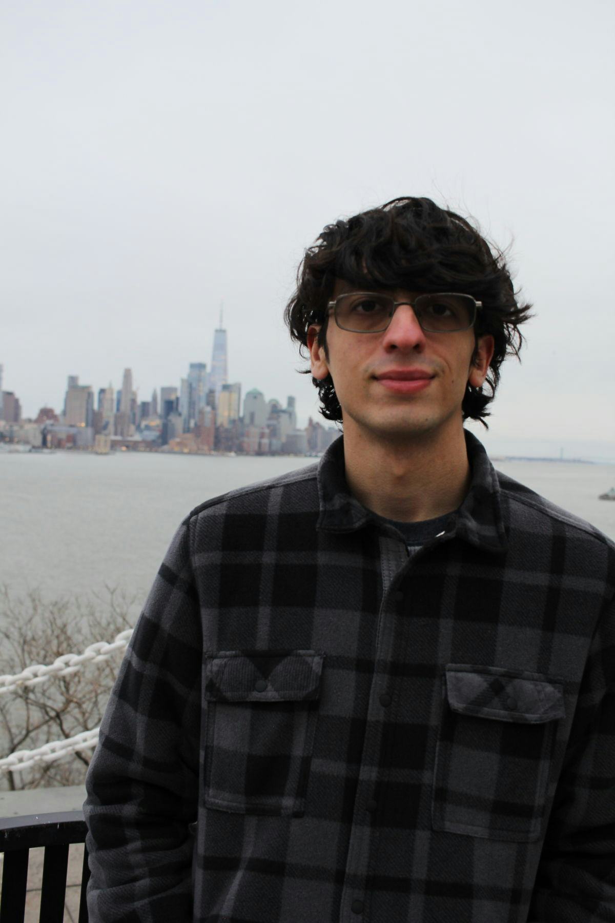 A profile of Angel Burgos '23 standing in front of the Hudson River, overlooking Manhattan