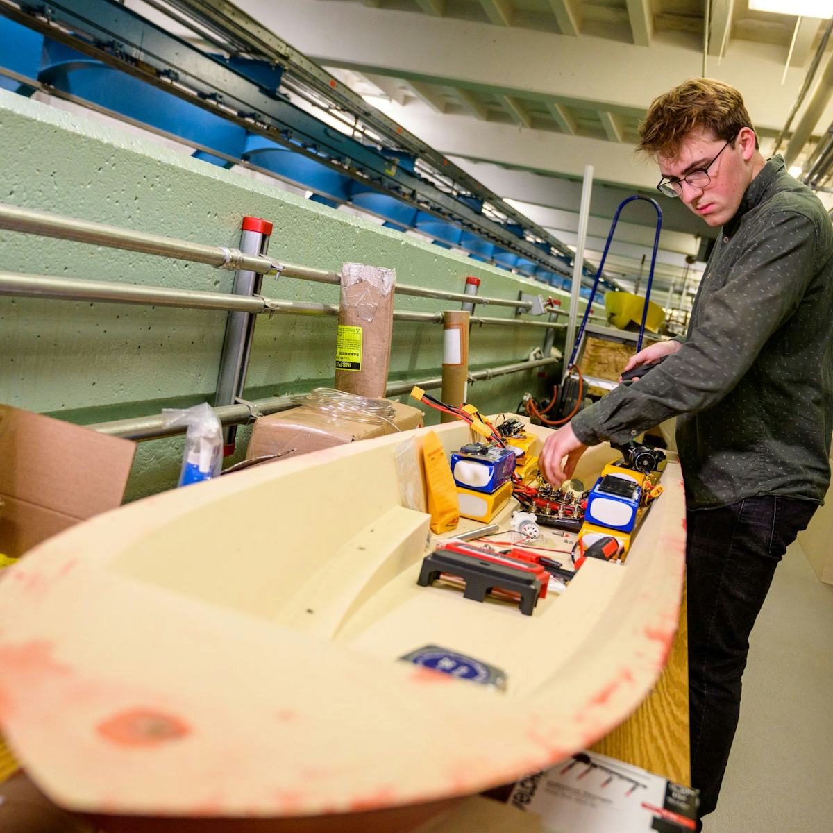 A student works on the electronics of a boat in Davidson Lab.