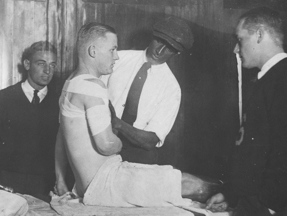 Old photo of a Stevens football player being bandaged around the arm.