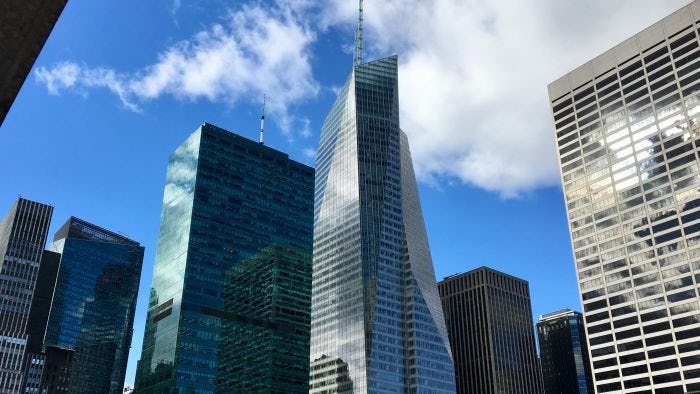 Picture taken from the ground, looking up at the Bank of America Tower in New York City on a partly sunny day.