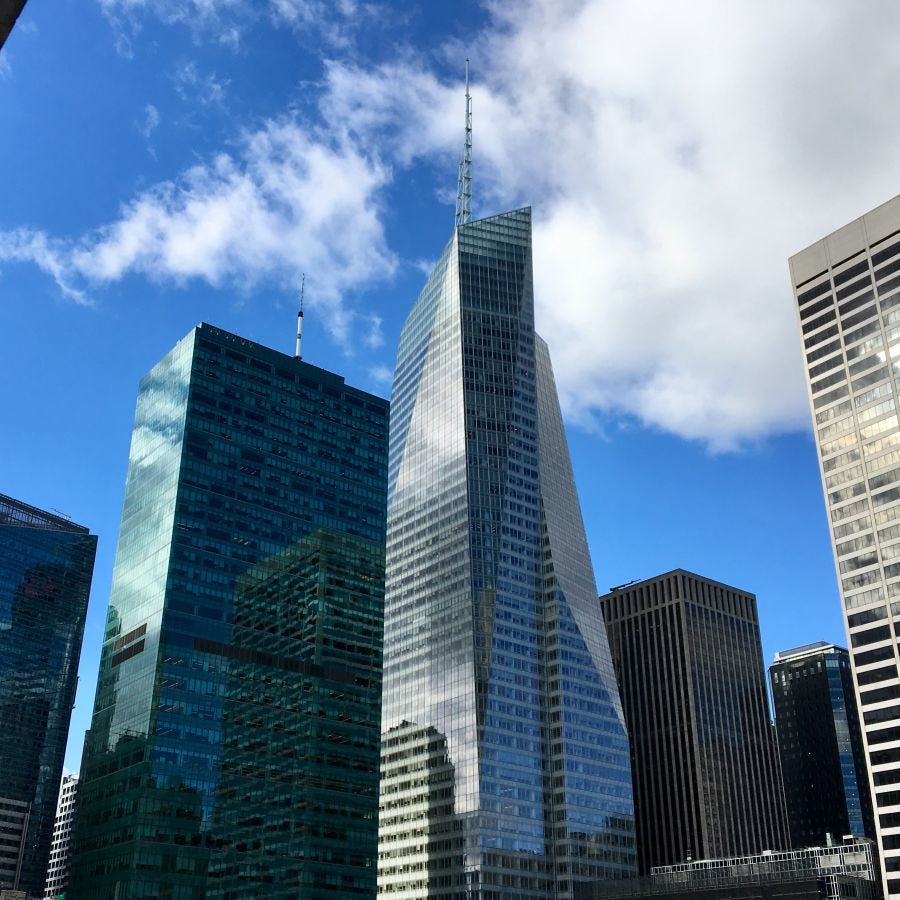 Picture taken from the ground, looking up at the Bank of America Tower in New York City on a partly sunny day.