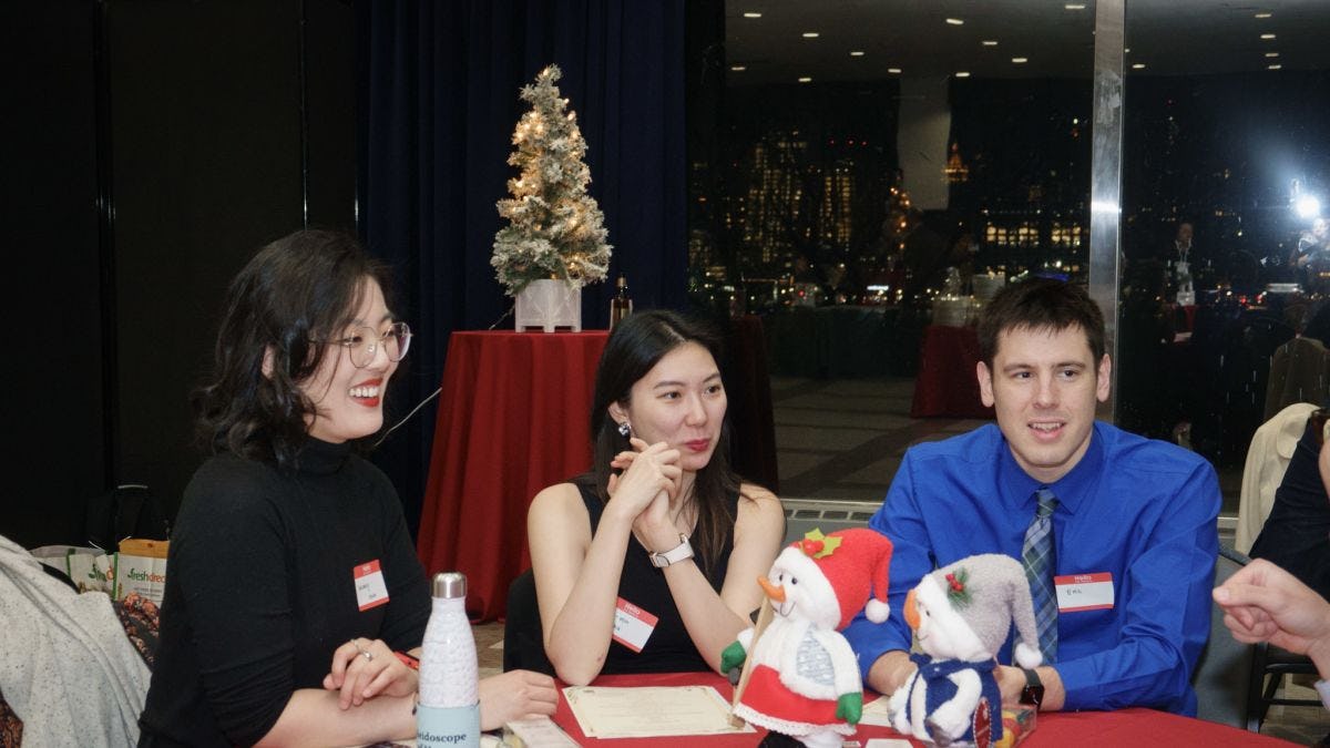 Three students sit at table with holiday decorations
