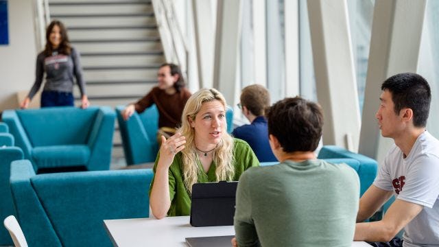 Students at table in University Center have a conversation.
