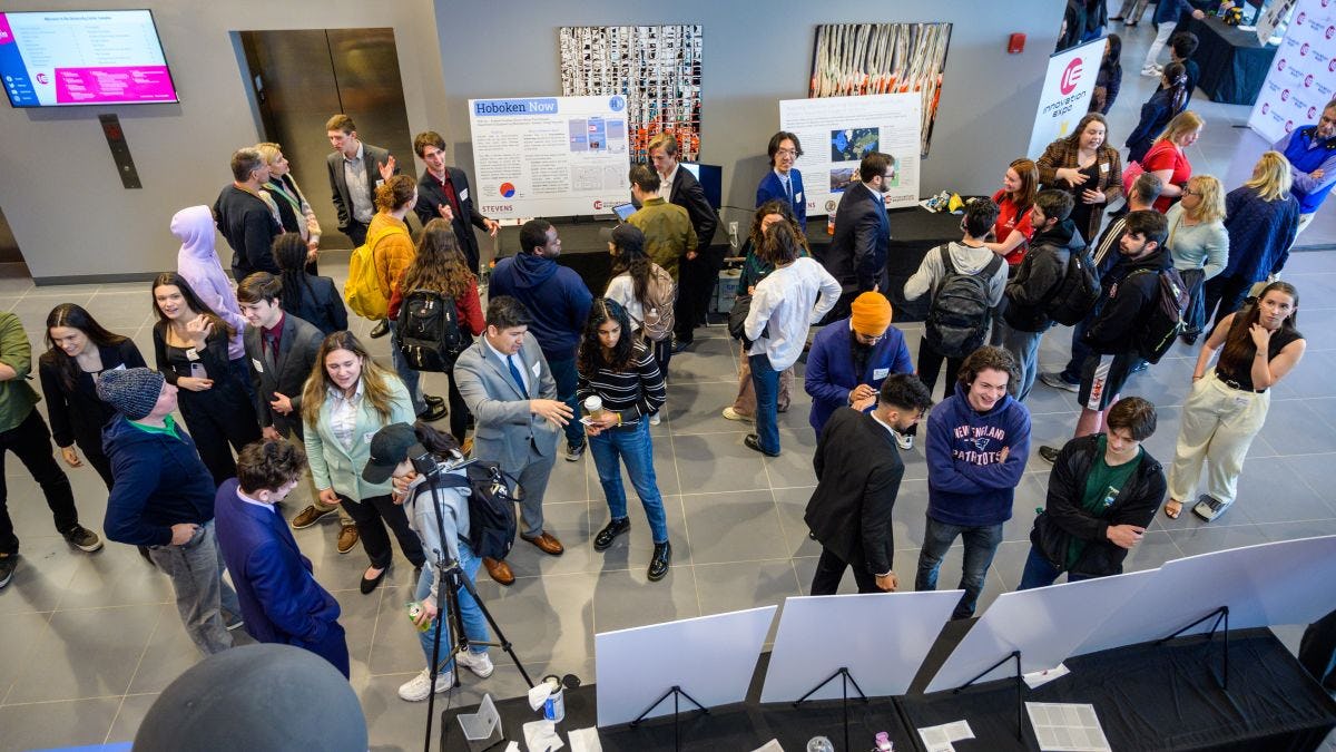 An overhead shot of students and faculty browsing project posters and presentations in the lobby of the UCC. 